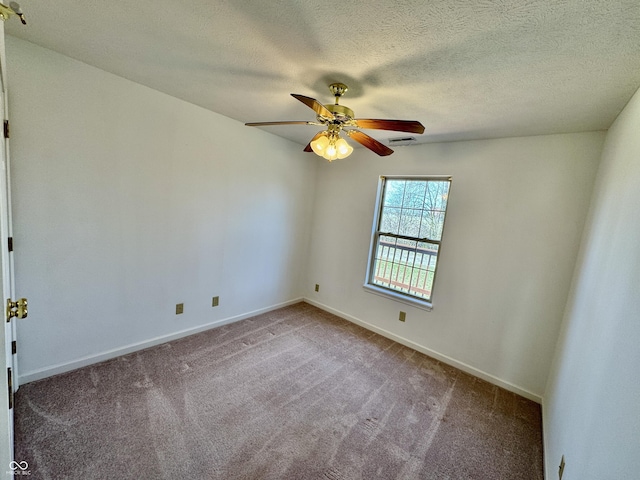carpeted spare room featuring a textured ceiling, visible vents, baseboards, and ceiling fan