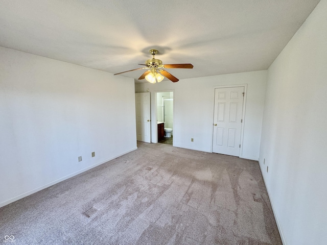 unfurnished bedroom featuring ensuite bathroom, a ceiling fan, baseboards, and carpet floors