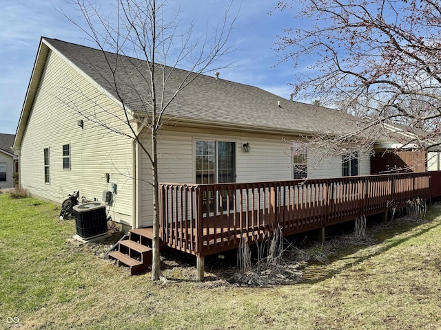 rear view of property with a wooden deck, central air condition unit, a shingled roof, and a yard
