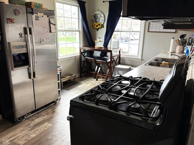 5368 Southeastern Ave, Indianapolis, IN 46203 - kitchen featuring wood finished floors, light countertops, a sink, stainless steel fridge, and black gas range oven