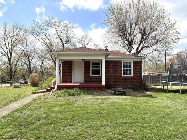 5368 Southeastern Ave, Indianapolis, IN 46203 - bungalow-style home featuring a trampoline, a front yard, fence, and brick siding