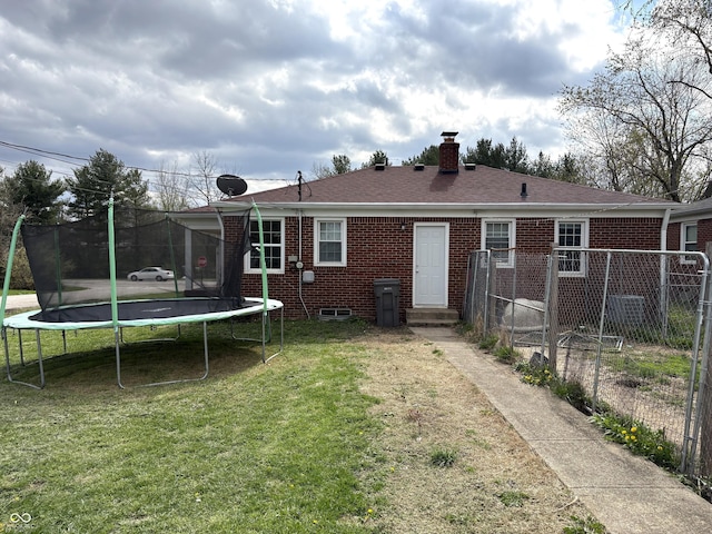 5368 Southeastern Ave, Indianapolis, IN 46203 - back of property with a trampoline, a yard, fence, brick siding, and a chimney