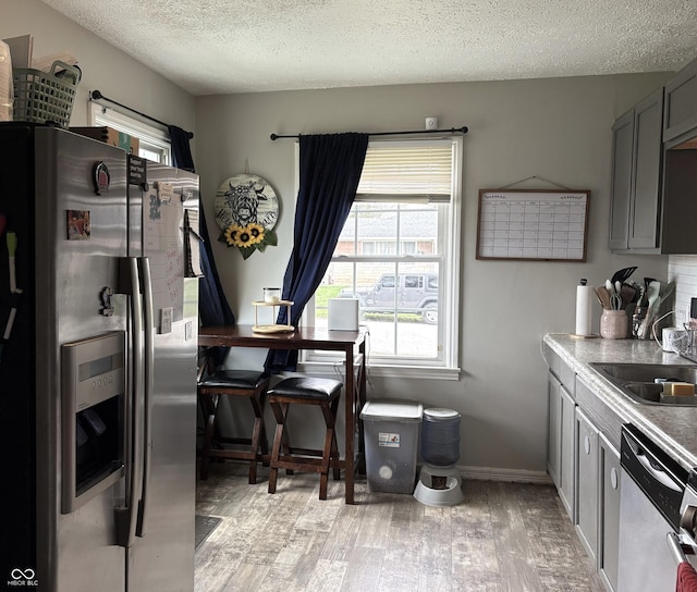 5368 Southeastern Ave, Indianapolis, IN 46203 - kitchen featuring a sink, light wood-type flooring, appliances with stainless steel finishes, a textured ceiling, and gray cabinetry