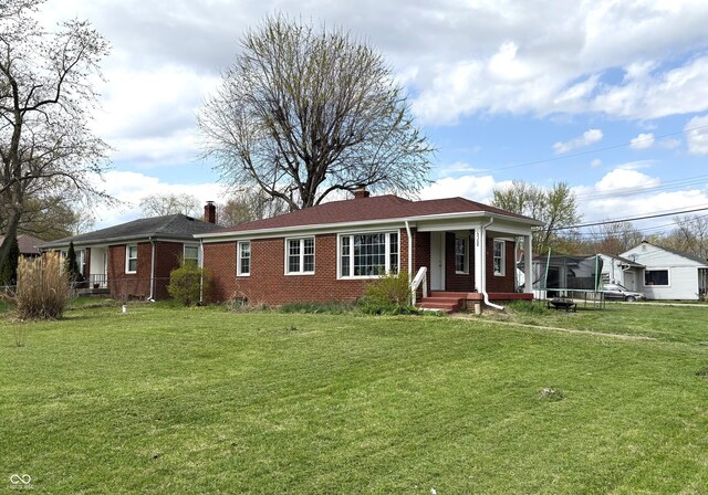 5368 Southeastern Ave, Indianapolis, IN 46203 - ranch-style house with a trampoline, a front yard, brick siding, and a chimney
