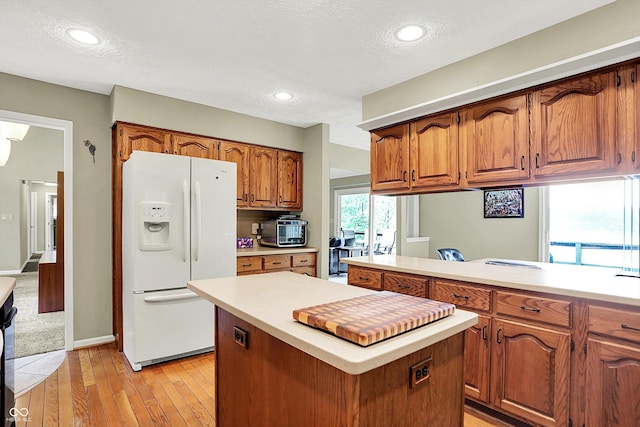 22 Point Ln, Arcadia, IN 46030 - kitchen with white fridge with ice dispenser, light countertops, light wood-type flooring, brown cabinets, and a center island