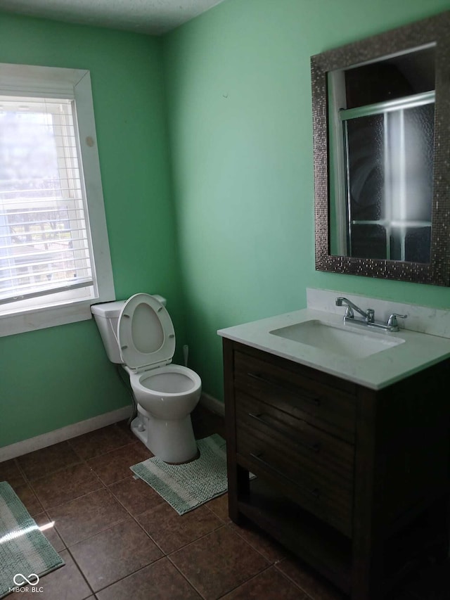 full bathroom featuring a shower stall, baseboards, toilet, vanity, and tile patterned flooring