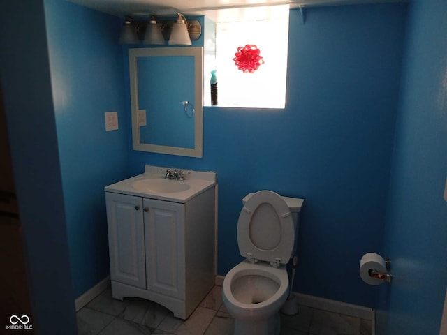 bathroom with baseboards, toilet, and vanity