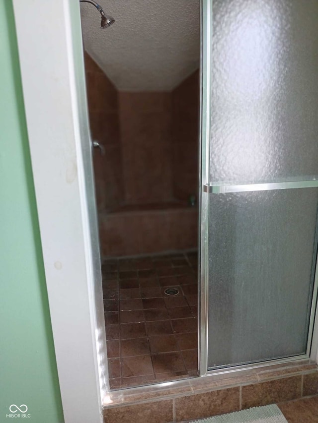 full bathroom featuring a shower stall and a textured ceiling