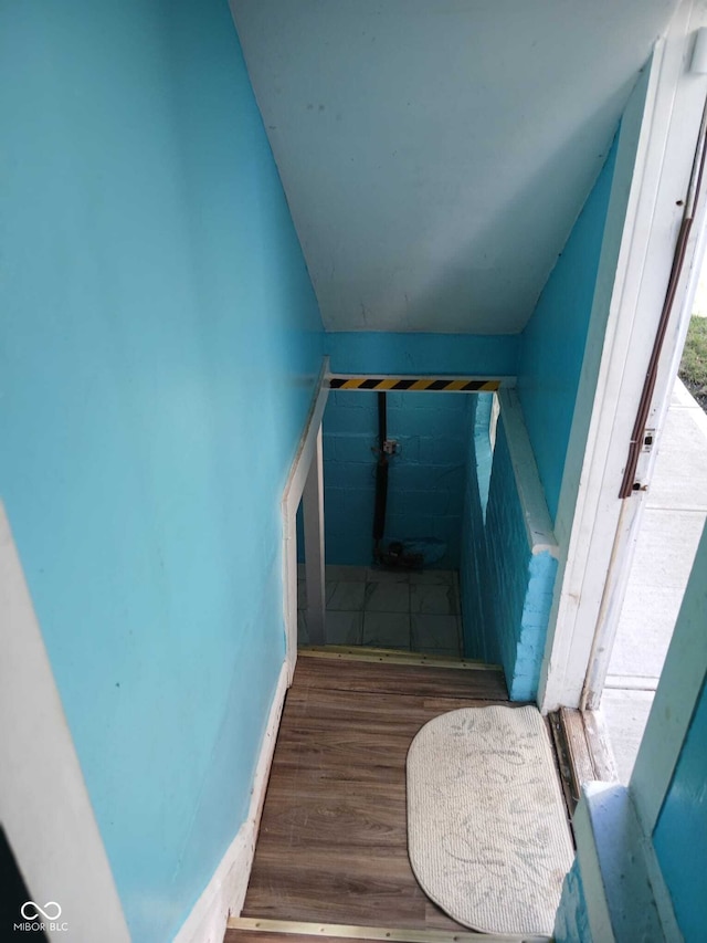 stairway featuring lofted ceiling and wood finished floors