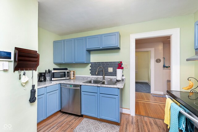 kitchen featuring blue cabinets, a sink, light wood-type flooring, light countertops, and appliances with stainless steel finishes