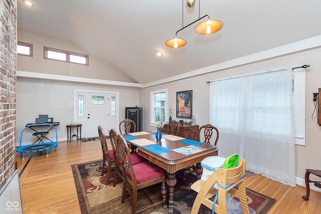 dining room with baseboards, wood finished floors, and high vaulted ceiling