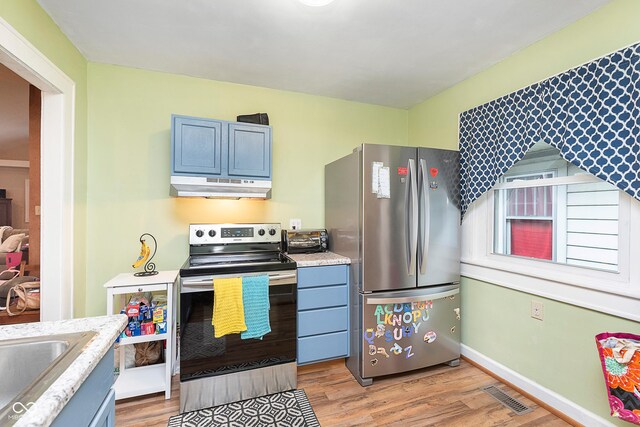 kitchen with stainless steel appliances, a sink, visible vents, light wood-style floors, and under cabinet range hood