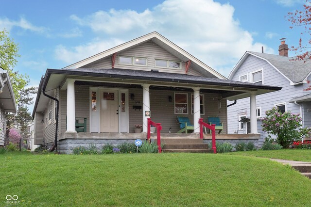 bungalow-style house with a front yard and covered porch
