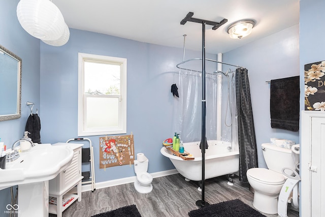 bathroom with shower / tub combo with curtain, wood finished floors, and toilet