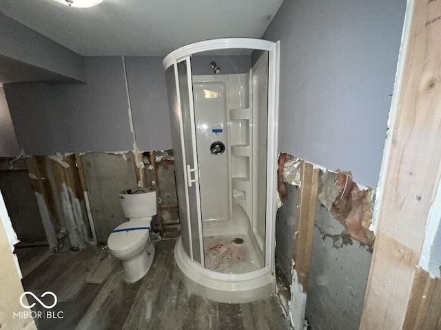 full bathroom with toilet, wood finished floors, and a stall shower