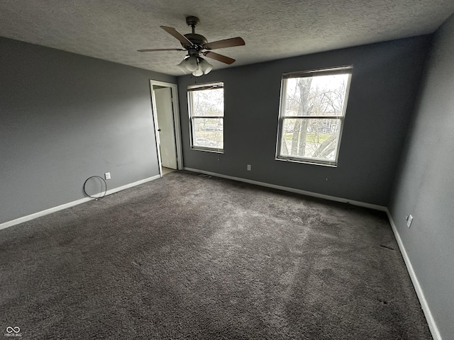 carpeted spare room featuring a textured ceiling, a ceiling fan, and baseboards