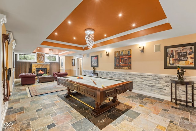 10821 Club Point Dr, Fishers, IN 46037 - recreation room featuring a stone fireplace, stone tile flooring, wainscoting, and a raised ceiling