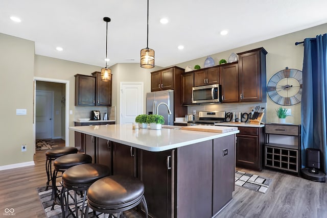 1684 Beach St, Greenwood, IN 46143 - kitchen featuring light countertops, a center island with sink, dark brown cabinets, appliances with stainless steel finishes, and wood finished floors