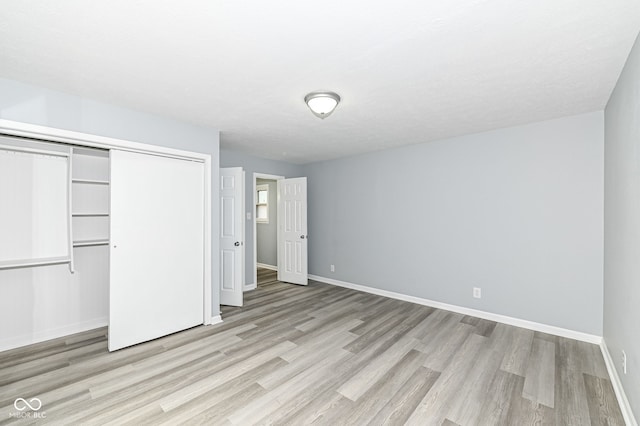 unfurnished bedroom with a closet, baseboards, and light wood-style floors