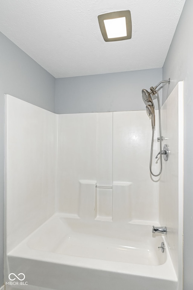 bathroom featuring washtub / shower combination and a textured ceiling