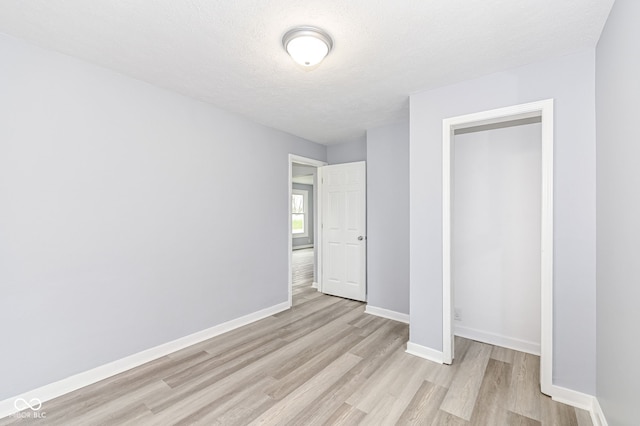 unfurnished bedroom with baseboards, light wood-style floors, and a textured ceiling
