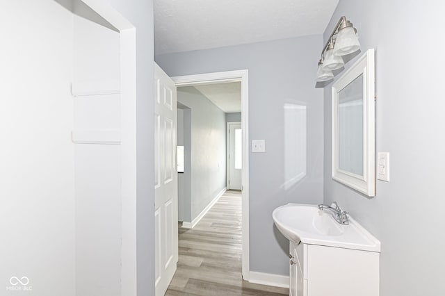 bathroom featuring a textured ceiling, vanity, baseboards, and wood finished floors