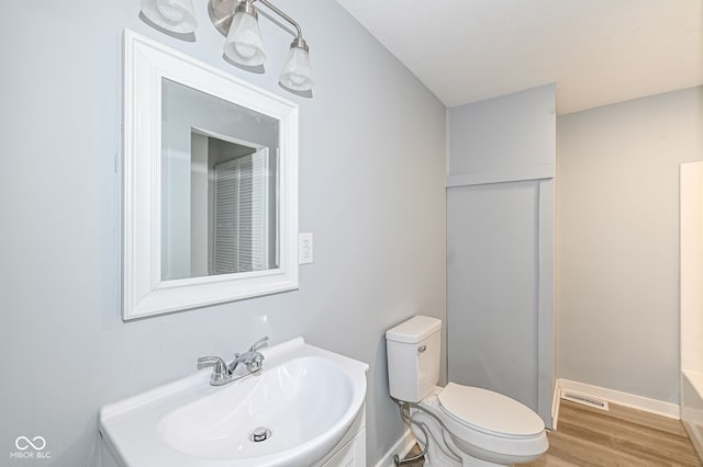 bathroom featuring vanity, wood finished floors, baseboards, a shower, and toilet