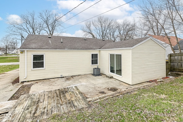 rear view of property featuring a patio, central AC unit, fence, and a shingled roof