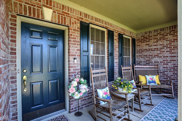 view of exterior entry featuring brick siding and a porch