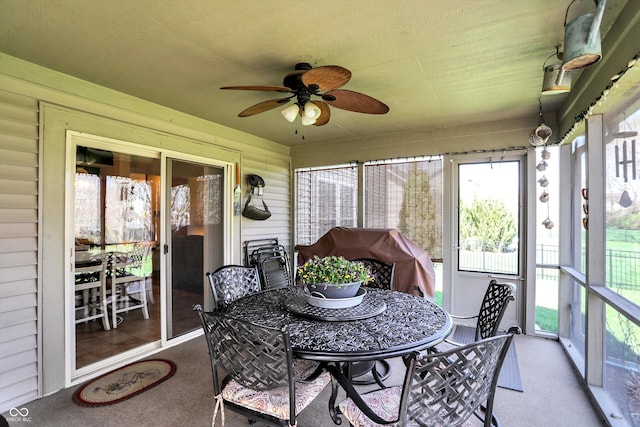 sunroom / solarium with outdoor dining area and a ceiling fan