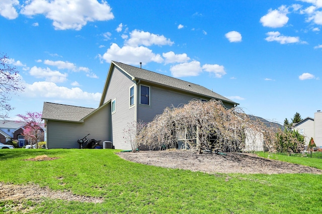 back of house featuring central AC unit and a lawn