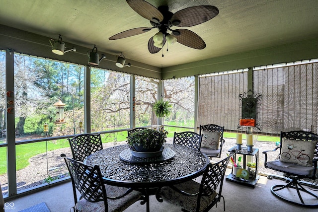 sunroom / solarium with outdoor dining space and a ceiling fan