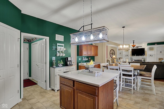 kitchen with a kitchen breakfast bar, visible vents, a center island, light countertops, and brown cabinets