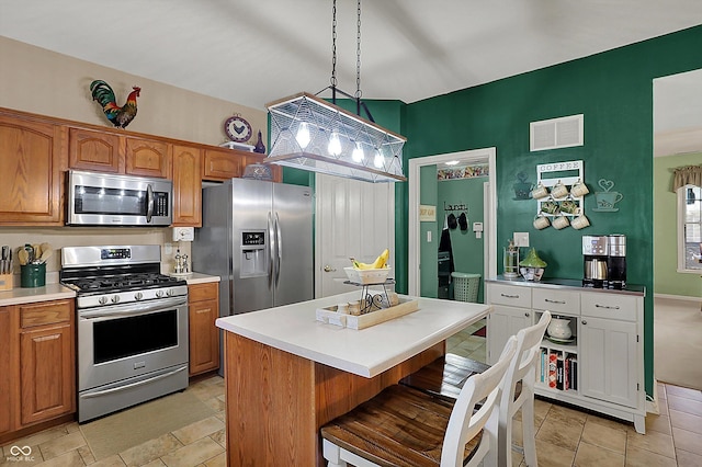 kitchen with stainless steel appliances, visible vents, brown cabinets, and light countertops