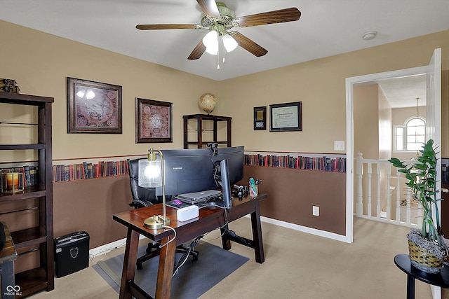 carpeted office featuring baseboards and a ceiling fan