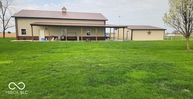 rear view of house featuring metal roof, a lawn, an outdoor structure, and an outbuilding