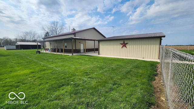 back of house with a lawn, fence, a patio area, and an outbuilding