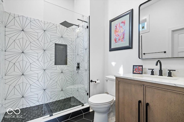 bathroom featuring vanity, tile patterned flooring, toilet, and tiled shower