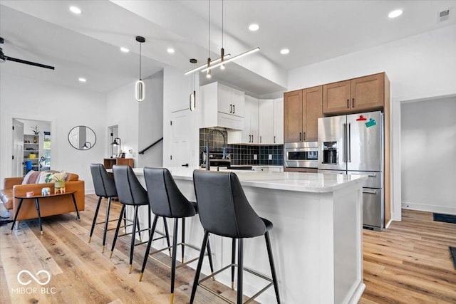 kitchen with a breakfast bar, light wood-type flooring, recessed lighting, appliances with stainless steel finishes, and backsplash