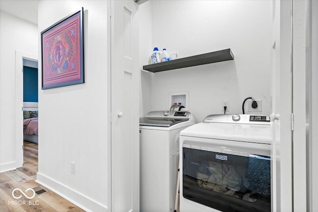 washroom featuring baseboards, laundry area, light wood-type flooring, and independent washer and dryer