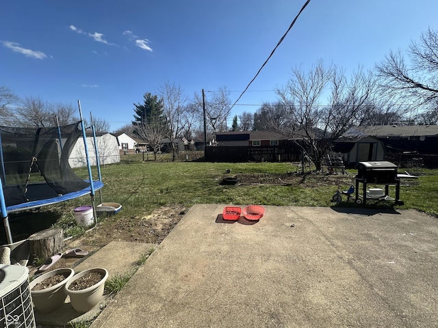 view of yard featuring a storage unit, an outbuilding, a trampoline, and fence