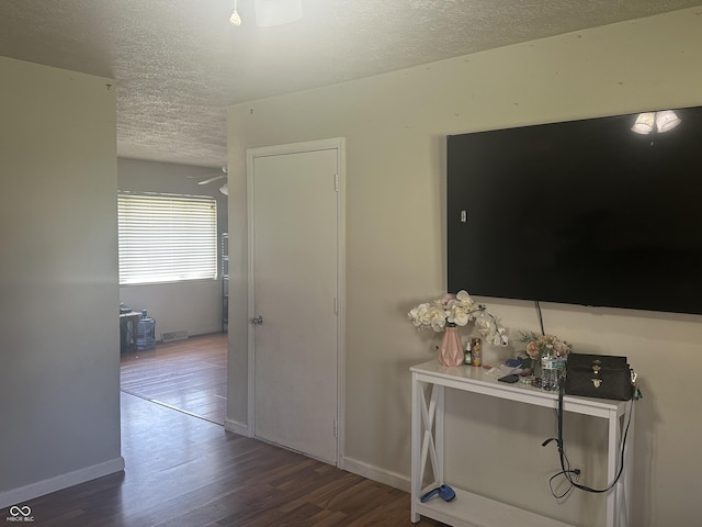 corridor featuring baseboards, a textured ceiling, and wood finished floors