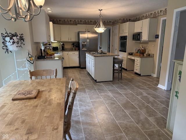 7341 Campfire Run, Indianapolis, IN 46236 - kitchen featuring appliances with stainless steel finishes, an island with sink, a chandelier, white cabinets, and pendant lighting