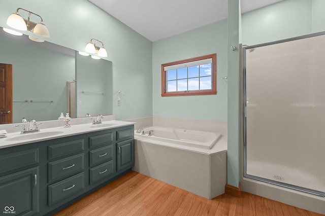 full bathroom featuring a shower stall, a sink, a bath, and wood finished floors