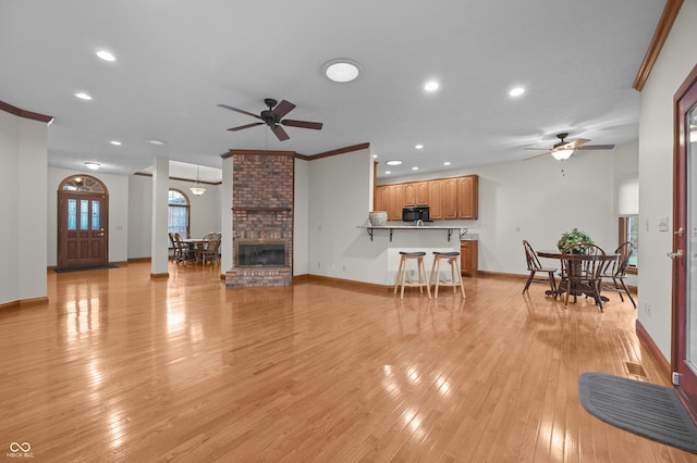 living area featuring visible vents, baseboards, light wood-style floors, and ceiling fan