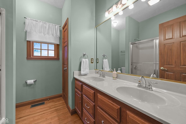 full bathroom with a sink, baseboards, visible vents, and wood finished floors
