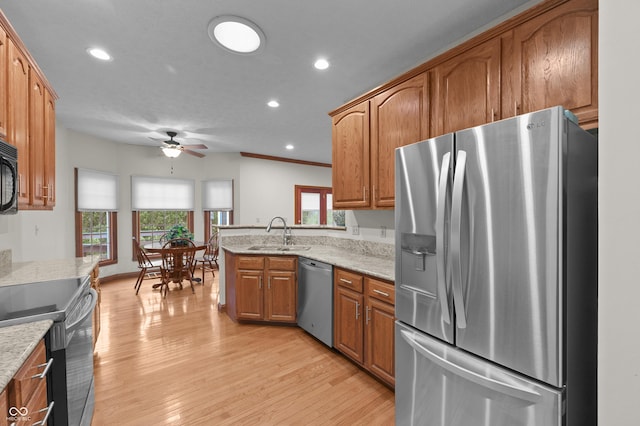 kitchen featuring ceiling fan, appliances with stainless steel finishes, a sink, light wood-type flooring, and brown cabinetry