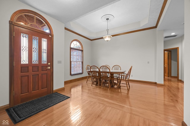 entryway with a tray ceiling, baseboards, light wood finished floors, and visible vents