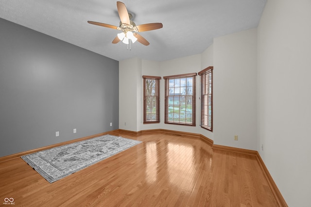 unfurnished room featuring baseboards, light wood-style flooring, and ceiling fan