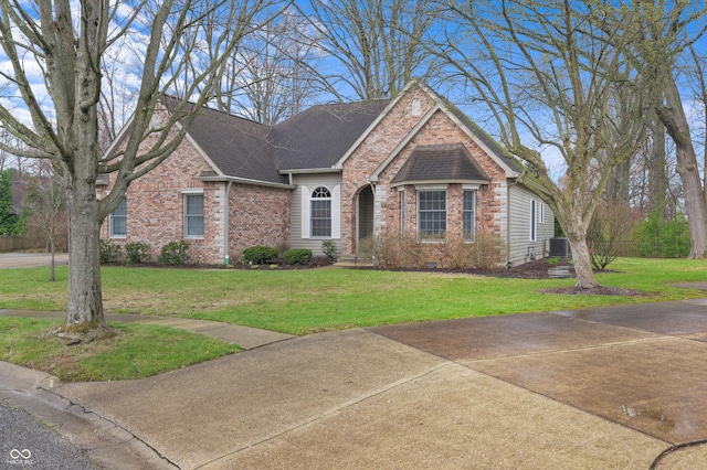 view of front facade featuring brick siding, a shingled roof, and a front lawn
